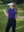 Model in klein blue women's performance solid polo holding a golf club outdoors
