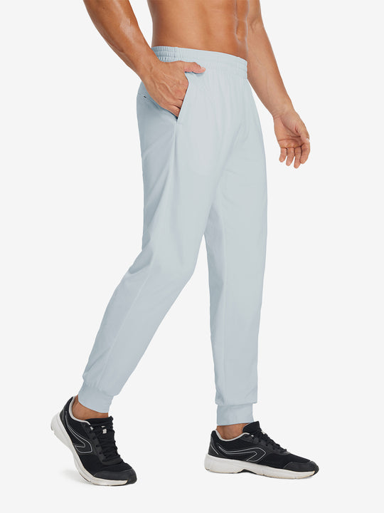 Side view of model with hand in pocket wearing lightweight traning track pants in misty grey.