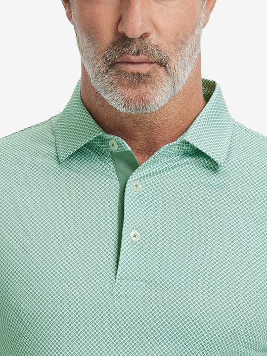 Close-up from nose to chest, showing collar and fabric pattern detail of the green plant polo shirt.