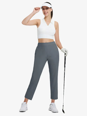 Full-body front view wearing golf hat and holding club in DARK GREY Women's 7/8 Ankle Golf Track Pants.