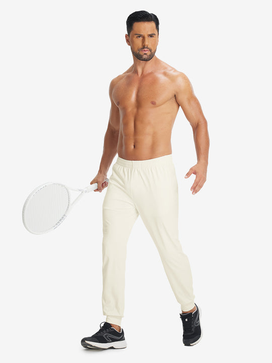 Model holding tennis racket wearing lightweight traning track pants in cream.