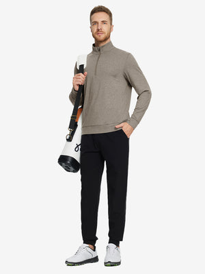 Model carrying a tennis bag, wearing brown melange quarter zip melange pullover in full-body view.