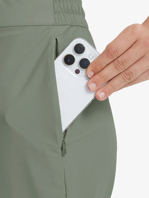 Detail shot of front side pocket holding an iPhone in OLIVE GREEN Women's 7/8 Ankle Golf Track Pants.