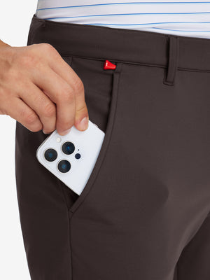 Side pocket detail of Golf Lightweight Fleece Lined Dress Pants in coffee brown, holding smartphone
