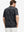 Back half-body of model in black splatter stretch printed collarless henley golf shirts