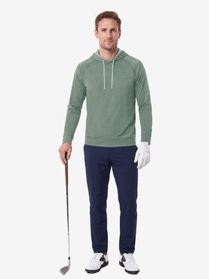 Full body model holding golf gear outdoors, heather midlayer golf hoodies in celadon green heather