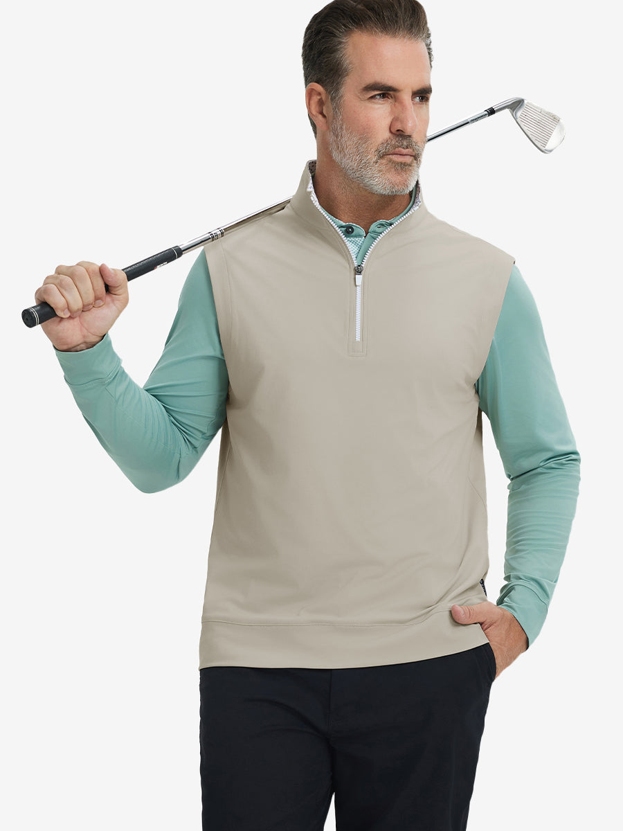 Model holding golf club, wearing print collar quarter zip golf vest in khaki light, upper body view.