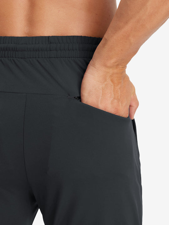 Back view of model with hand in pocket wearing lightweight traning track pants in black.