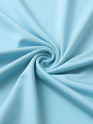 Close-up of light blue 4 way stretch jacquard polo fabric texture highlighting intricate woven pattern and elasticity.