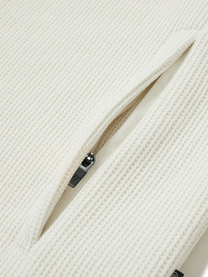 Close-up of jacket pocket showing fine stitching and insulation detail, textured insulated winter jacket, beige.