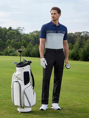 Model in black water resistant everyday pants standing with a golf bag outdoors, full-body shot